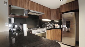 Une cuisine moderne avec des meubles en bois, un réfrigérateur en acier inoxydable, un four à micro-ondes encastré et une cuisinière à gaz.