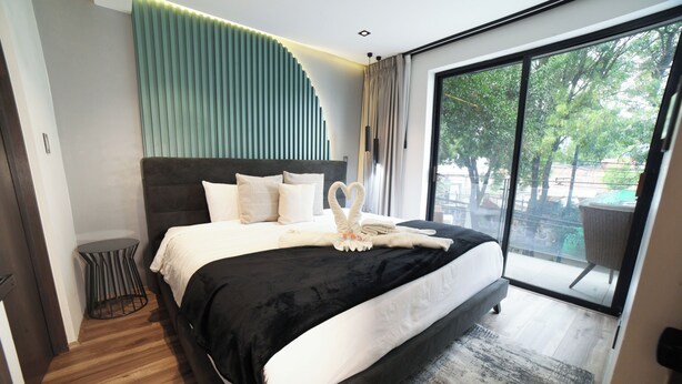 Une chambre à coucher moderne, dotée d’un grand lit, d’une table de chevet ronde et offrant une vue sur l’extérieur grâce à une grande fenêtre.