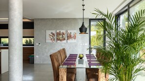 A modern dining area with a glass table, leather chairs, and abstract art on the wall. - Villa Aria by Villas Guide (Višnjan)