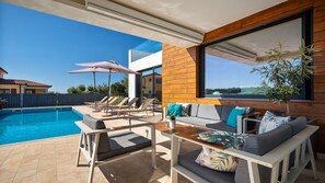 A modern outdoor living area with a pool, lounge chairs, a sofa, and a table. - Villa Aria by Villas Guide (Višnjan)