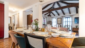 A dining area with a wooden table set for six, surrounded by chairs.