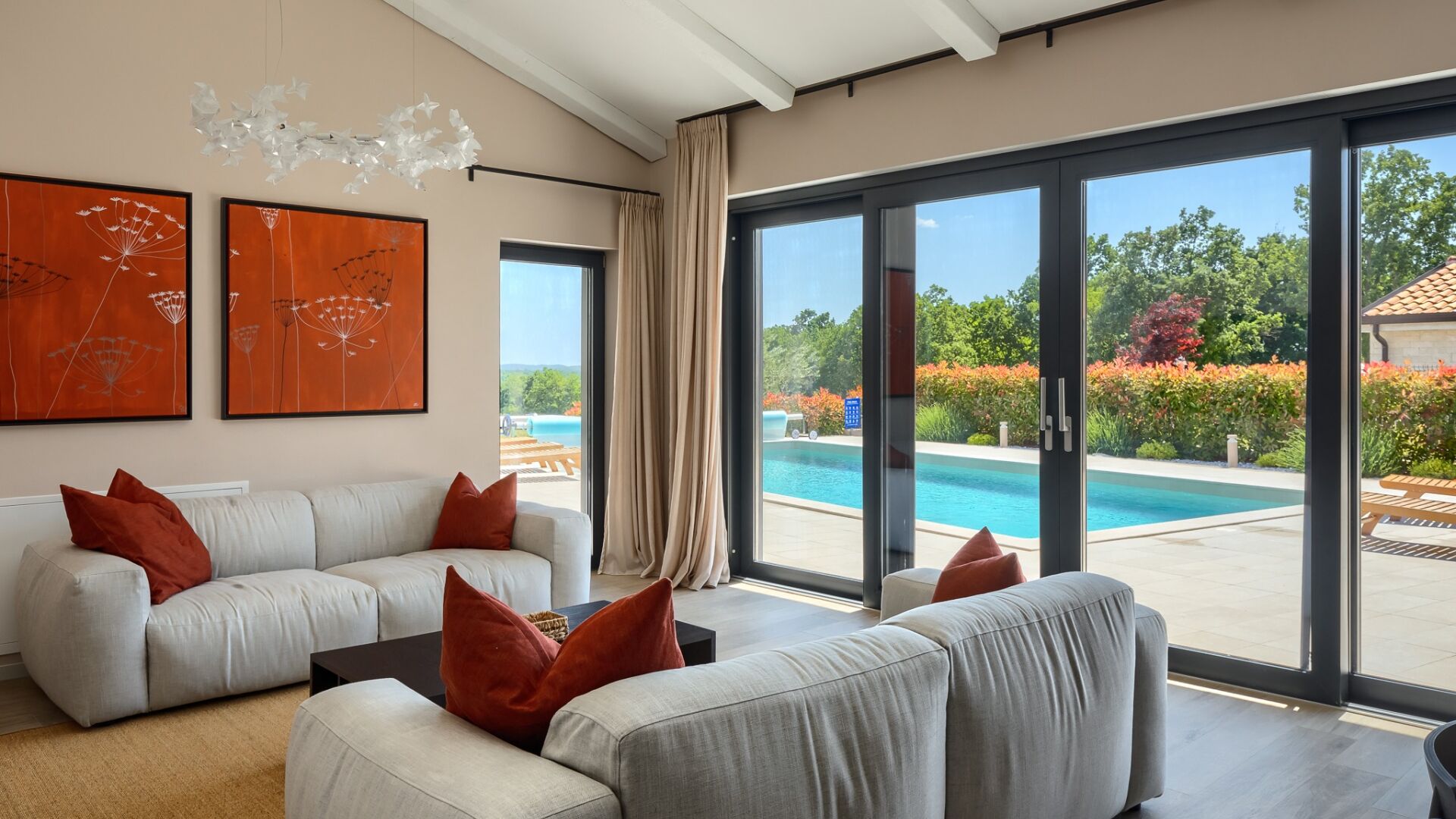 A modern living room with a large sliding glass door leading to a pool area.
