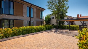 A courtyard with a paved walkway, modern buildings, and well-maintained hedges.