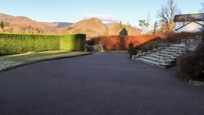 Une allée pavée mène à un escalier en pierre, et offre une vue sur les montagnes en arrière-plan.