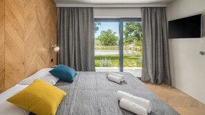 Una habitación de hotel moderna con una cama, un televisor y vistas a una piscina.