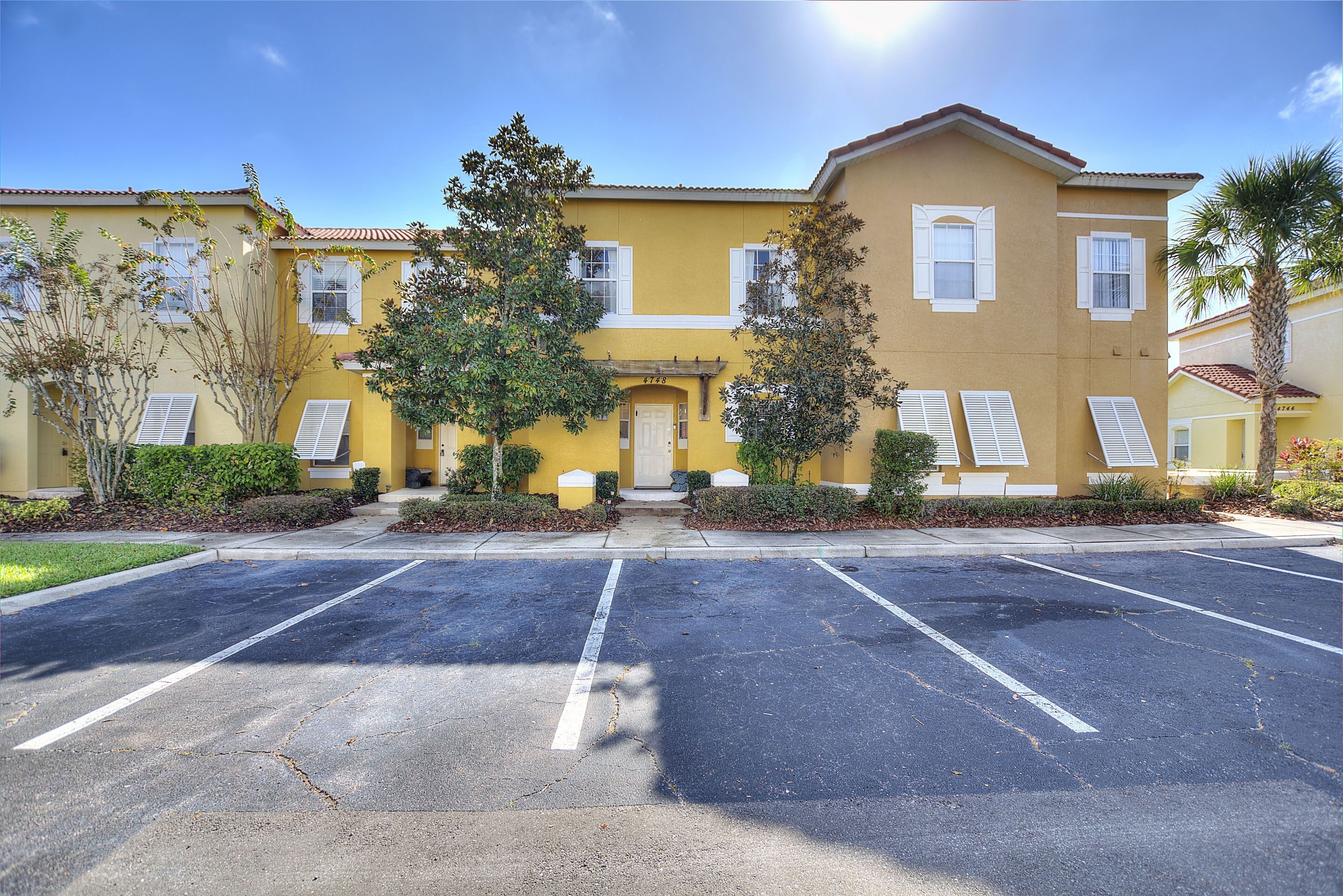 A yellow building with a parking lot in front.