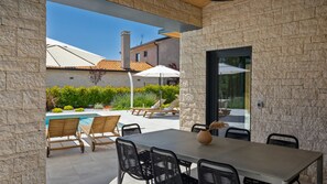 An outdoor patio with a pool, lounge chairs, and a dining table with chairs.