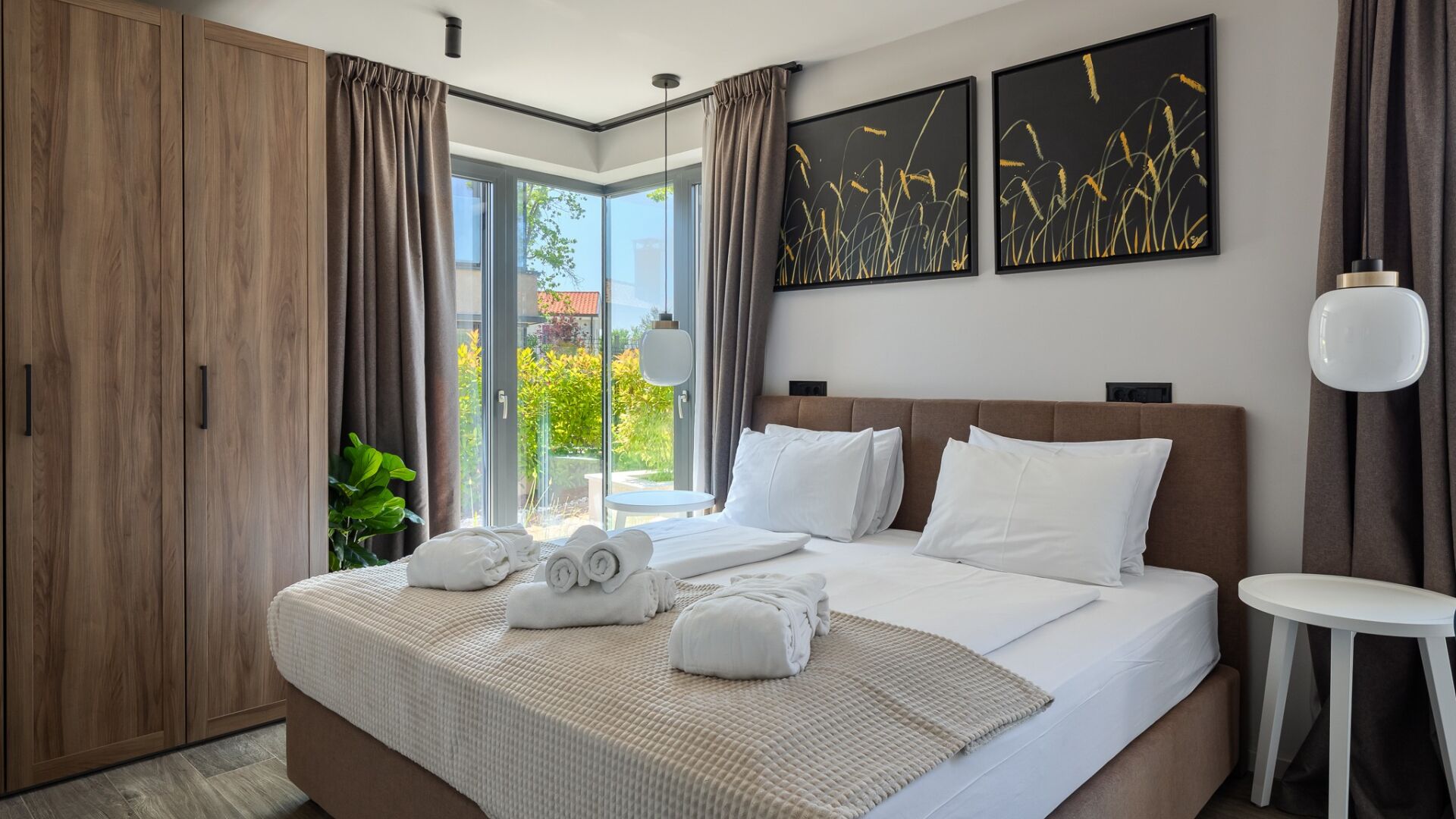 Een moderne hotelkamer met een groot bed, uitzicht op groen en een balkon.