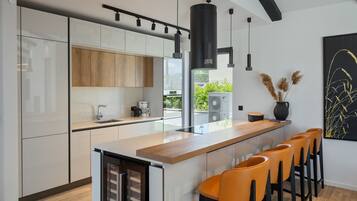 Een moderne keuken met een centraal eiland, barkrukken en een groot raam.