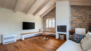 Ein modernes Wohnzimmer mit Steinwand, Flachbildfernseher, Kamin und einer Holzbank.