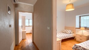 Ein Schlafzimmer mit Bett, Nachttisch, Lampe und einem Fenster.