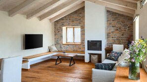 A loft-style room with a stone wall, wooden beams, a flat-screen TV, a fireplace, and a bench. - Villa Casa Bastiani by Villas Guide (Marušici)