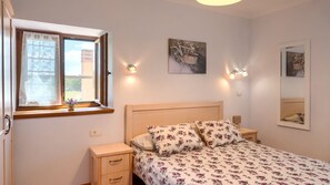 A bedroom with a bed, bedside tables, a window with curtains, wall-mounted lights, and artwork. - Villa Casa Bastiani by Villas Guide (Marušici)