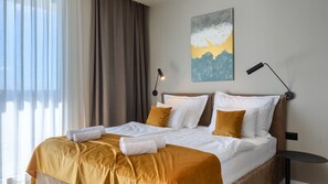 Ein Hotelzimmer mit Bett, Nachttisch, Lampe und einem Gemälde an der Wand.