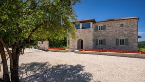 A stone building with a gravel driveway and red flowers. - Villa Kave by Villas Guide (Grožnjan)