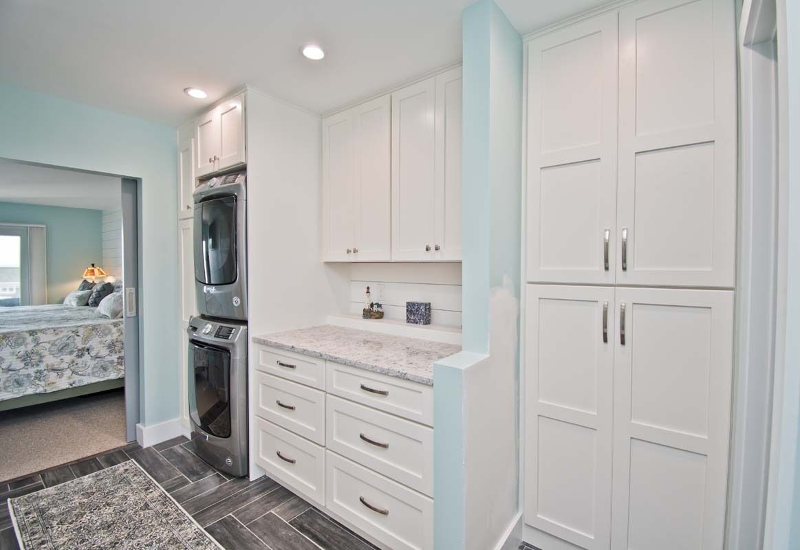 A modern kitchen with white cabinets, a built-in oven, and a granite countertop.
