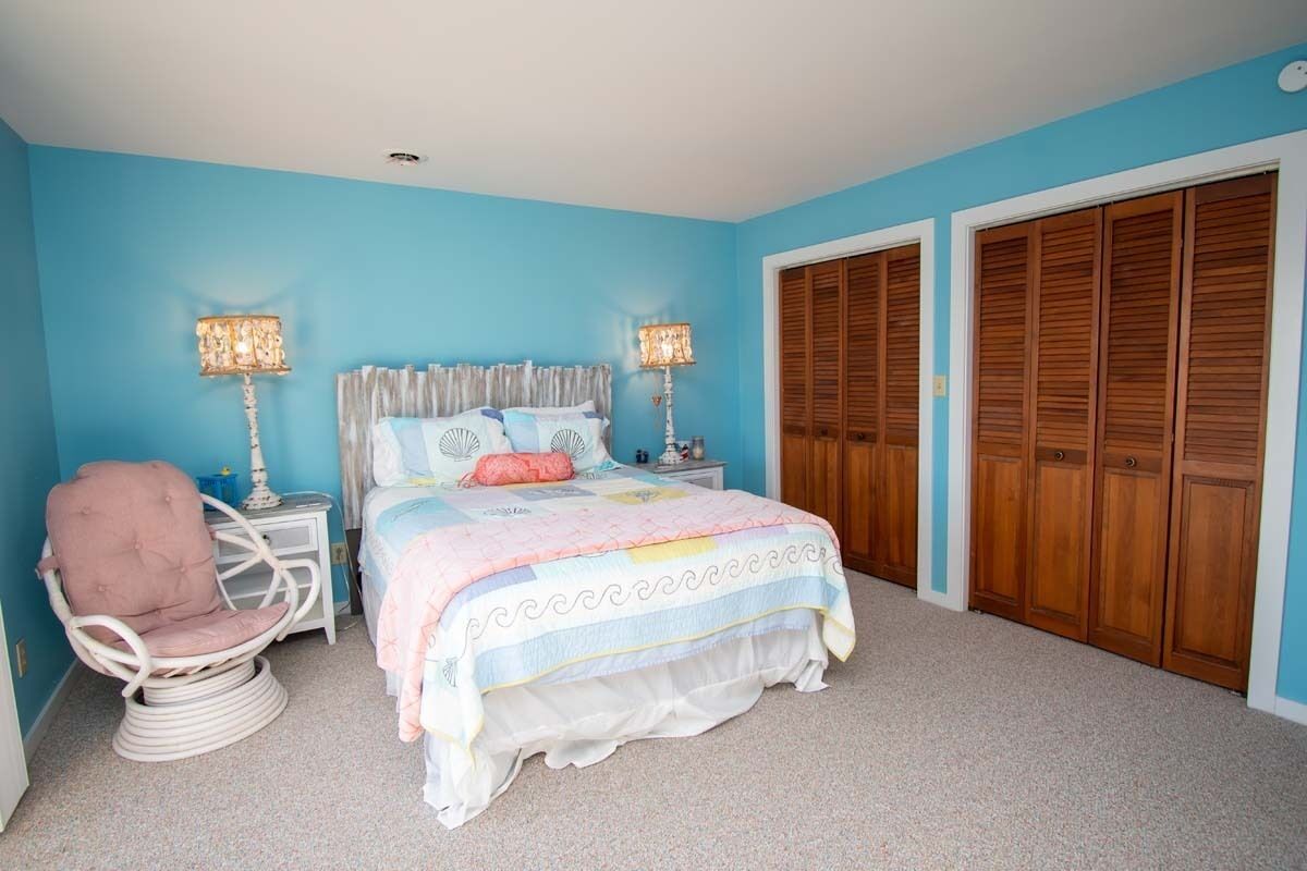 A bedroom with a bed, a chair, bedside tables, and a wardrobe.