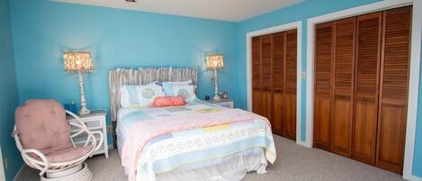 A bedroom with a bed, a chair, bedside tables, and a wardrobe.