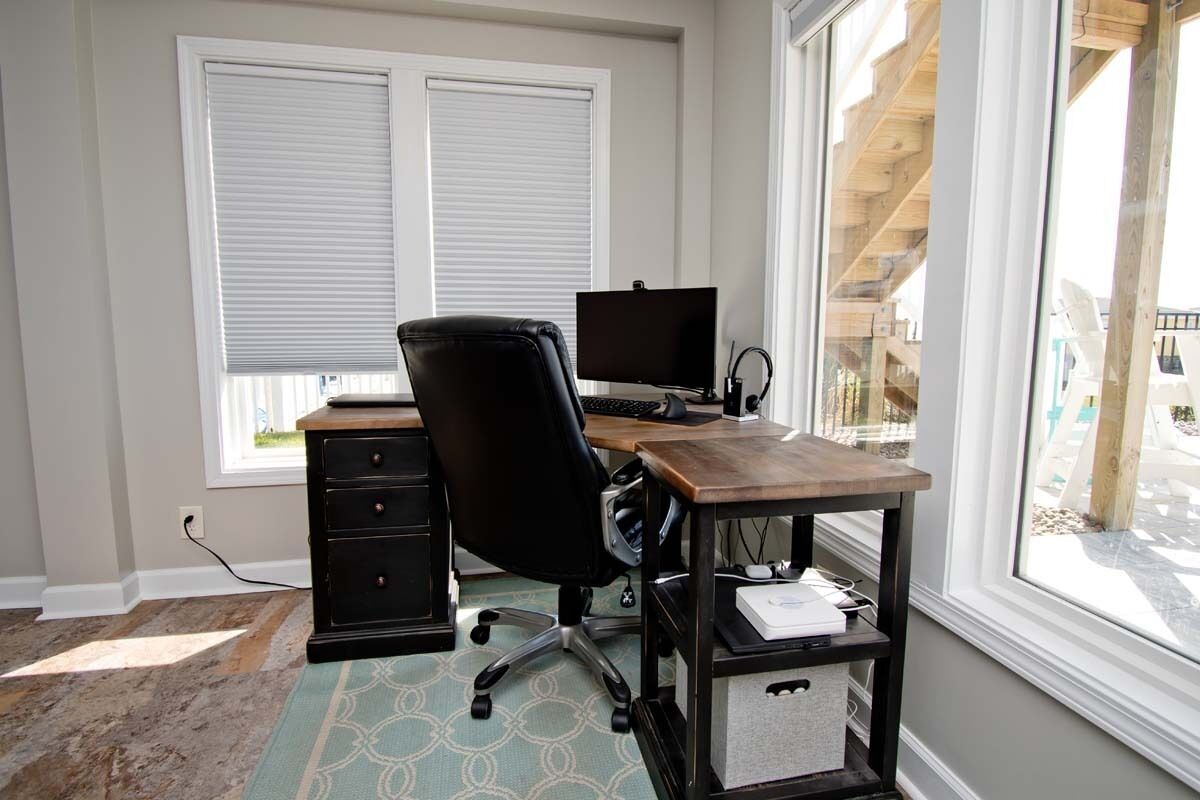 Een werkplek aan huis met bureau, stoel, computer en opbergruimte.