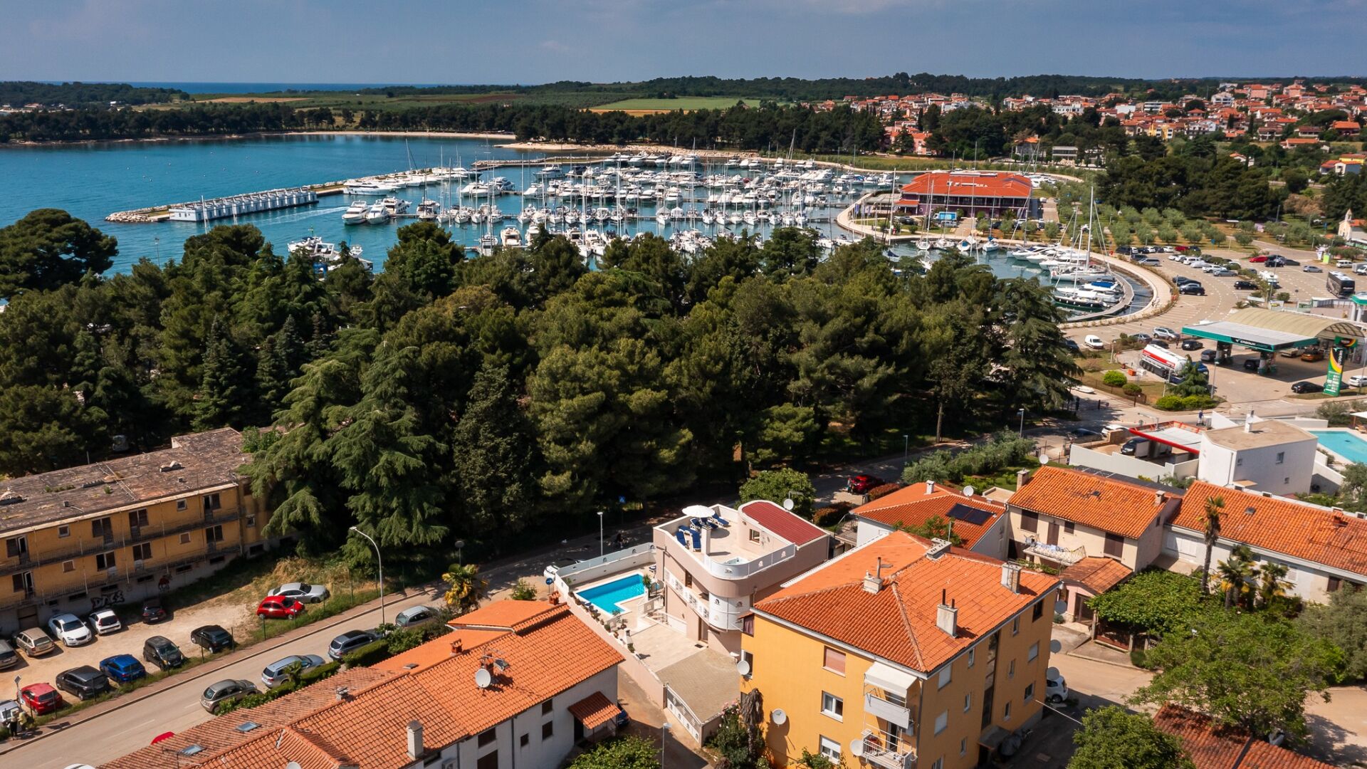 Un port de plaisance avec de nombreux bateaux, un bâtiment doté d’un toit rouge et une piscine.