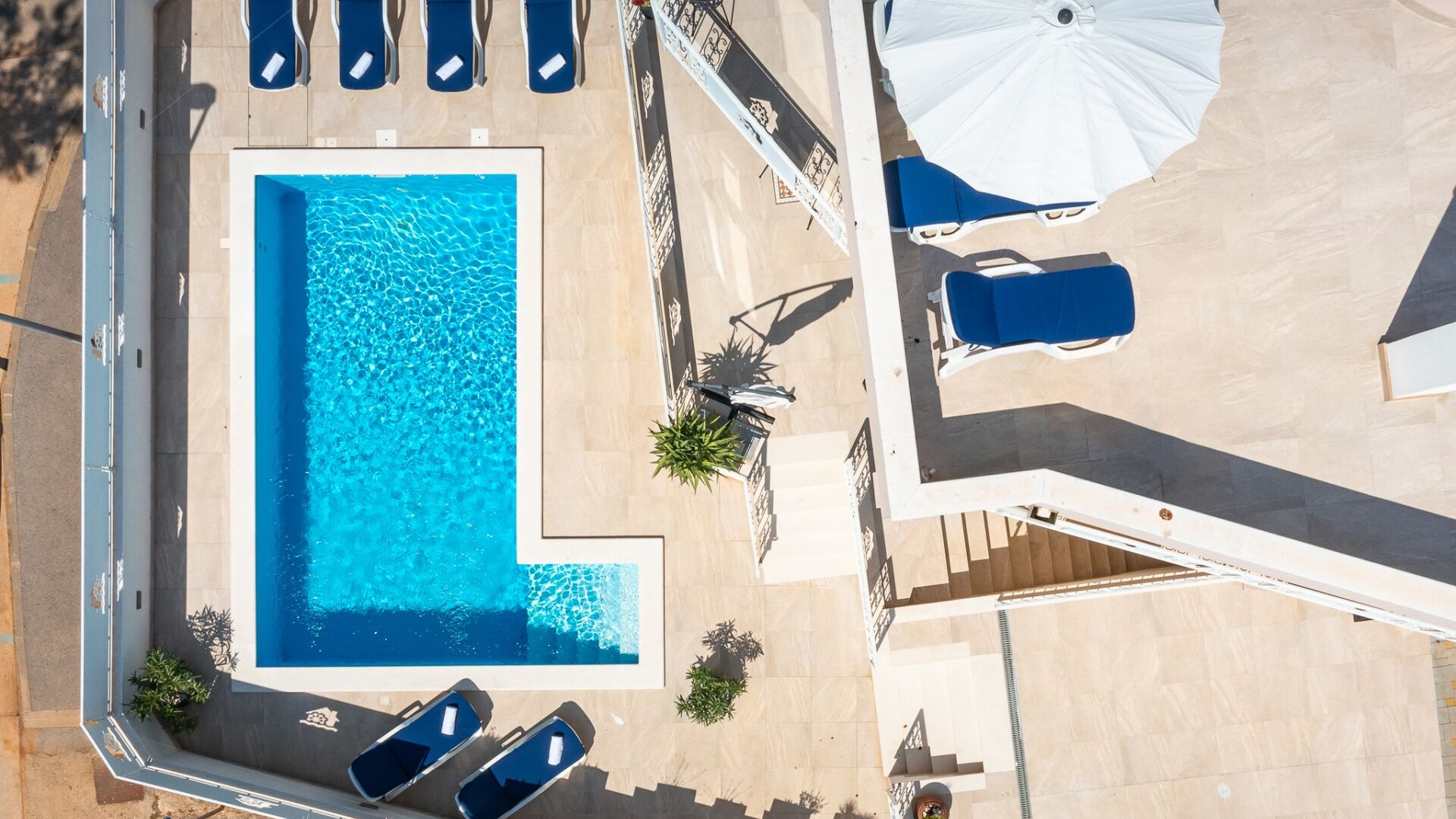 An aerial view of a swimming pool area with lounge chairs and umbrellas.