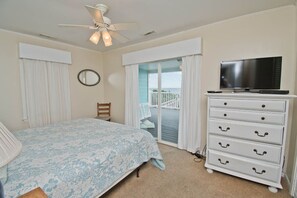 A bedroom with a bed, a dresser, a television, and a balcony with a view. - Decks Ahoy, Oceanfront House in Emerald Isle, NC! (Emerald Isle)