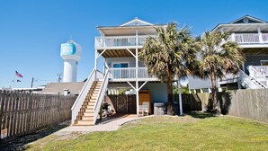 A two-story beachfront house with a balcony, a wooden fence, and a palm tree. - Dock Holiday, Oceanview House in Atlantic Beach, NC! (Atlantic Beach)
