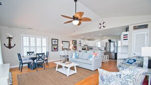 A spacious living area with a dining table, sofas, and a kitchen in the background. - Dock Holiday, Oceanview House in Atlantic Beach, NC! (Atlantic Beach)