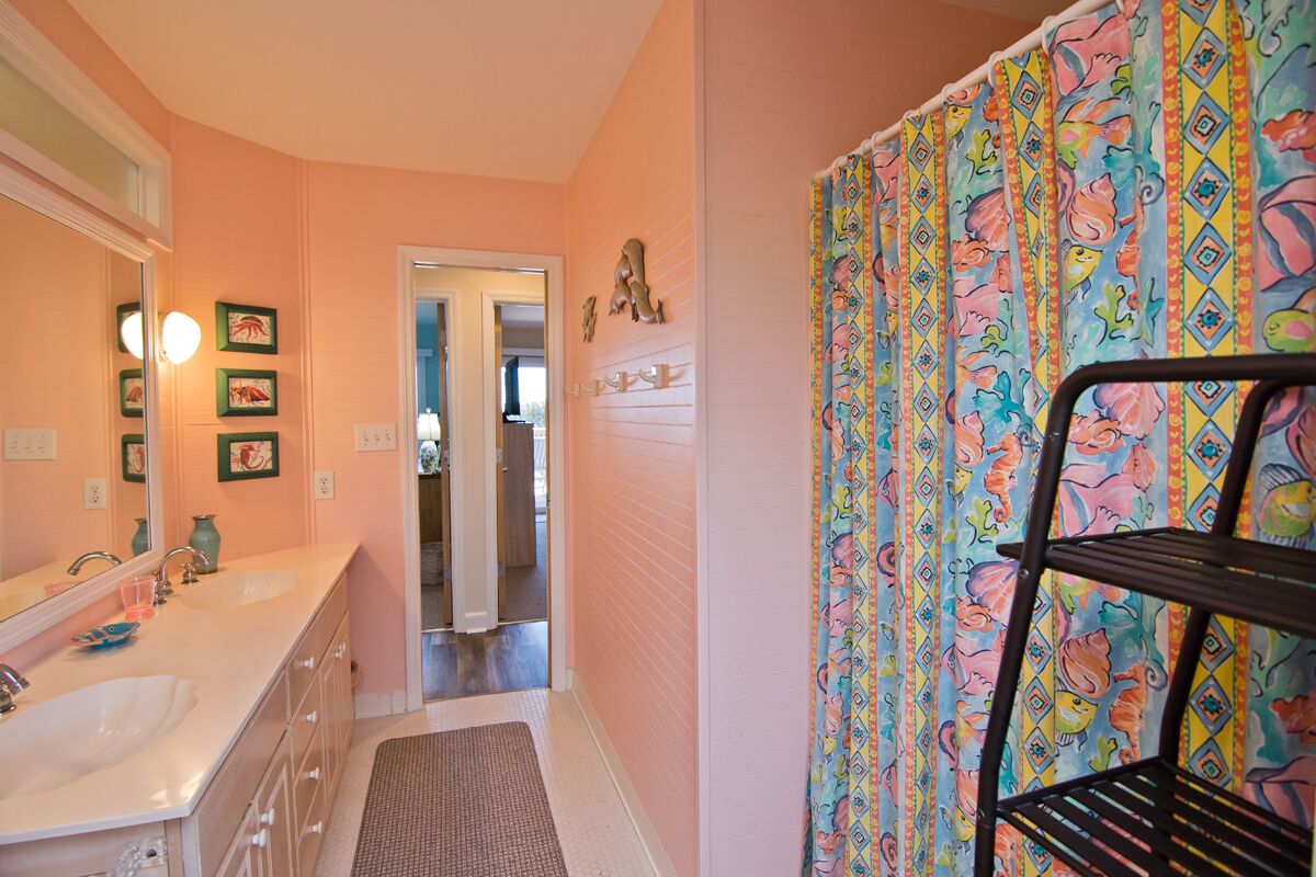A bathroom with two sinks, a mirror, and a shower curtain with a colorful pattern.