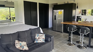 Una cocina moderna con refrigerador empotrado, una barra de madera y dos taburetes negros.