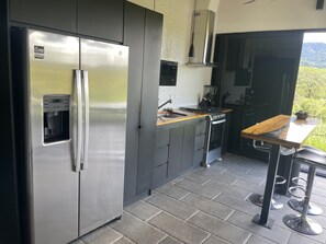 Ett modernt kök med ett kylskåp i rostfritt stål, en inbyggd kaffebryggare och en gasspis.