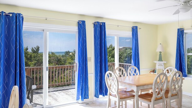 A balcony with a table and chairs, a ceiling fan, and a view of the ocean. - Dune Magic, Almost Oceanfront House in Emerald Isle, NC! (Emerald Isle)