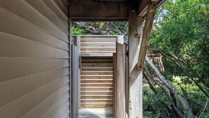 A wooden staircase leading to a covered outdoor area, surrounded by trees and greenery. - Dune Magic, Almost Oceanfront House in Emerald Isle, NC! (Emerald Isle)