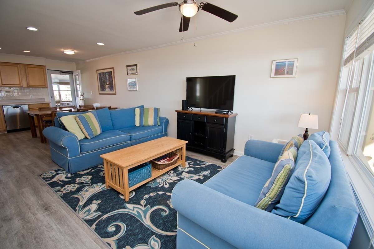 A living room with a blue sofa, a wooden coffee table, and a television.