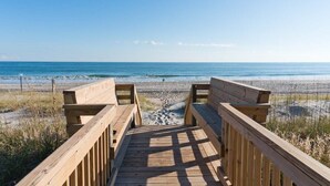 Ein hölzerner Gehweg führt zu einem Strand mit freiem Blick auf das Meer.