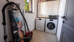 A laundry room with a vacuum cleaner, a washing machine, and a dryer. - Villa Alves by Villas Guide (Tar)