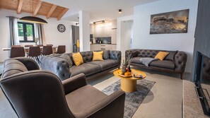 A modern living room with a sectional sofa, a coffee table with fruit, and a dining area with chairs. - Villa Alves by Villas Guide (Tar)