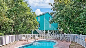 A turquoise building with a pool and white railings.