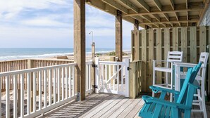 Une terrasse en bois offrant une vue sur la plage et l’océan.