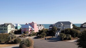 A coastal residential area with colorful houses, a clear sky, and a view of the sea. - Flip Flop Inn, Almost Oceanfront Duplex in Emerald Isle, NC! (Emerald Isle)