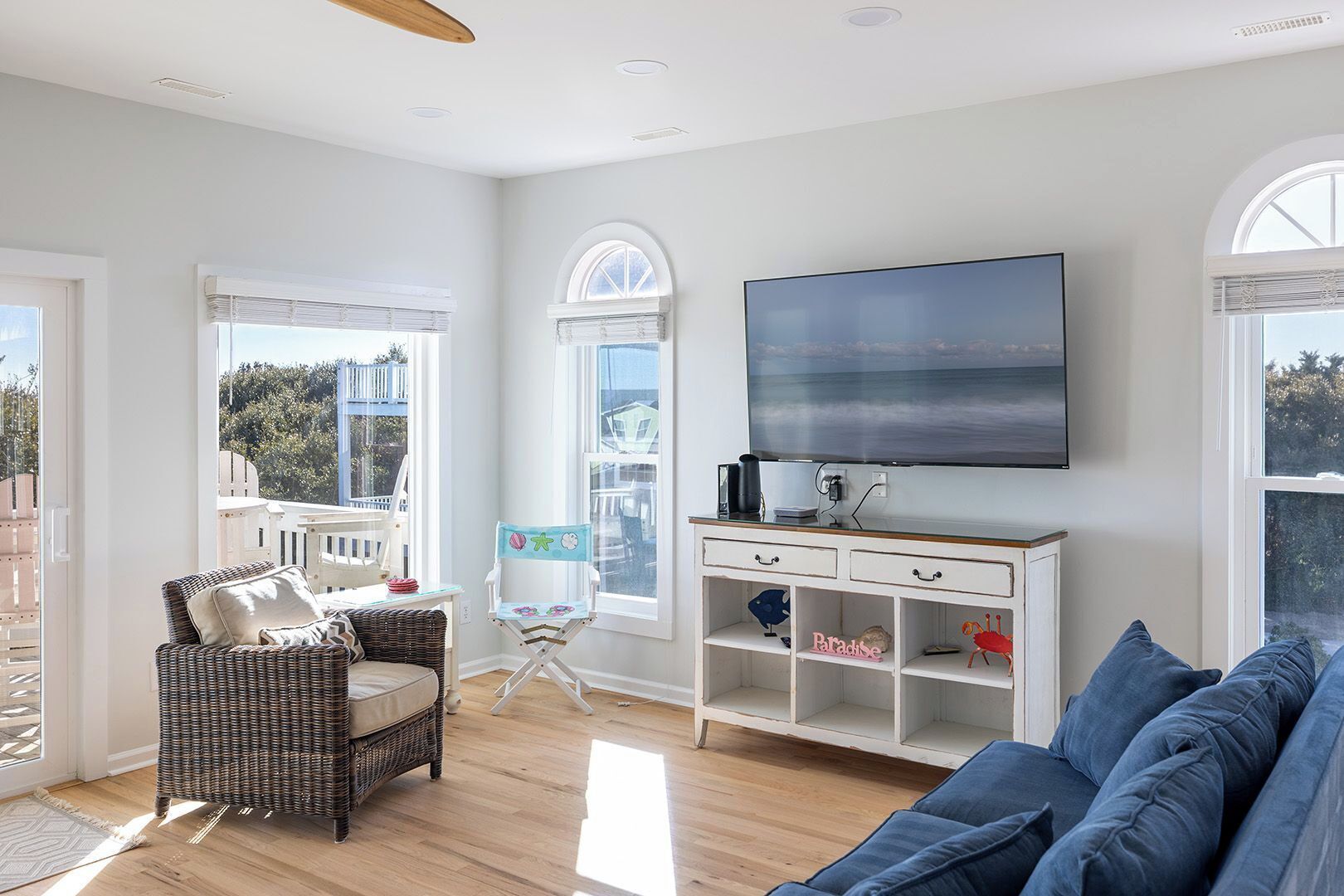 A living room with a large TV, wicker furniture, and a view of the outdoors.