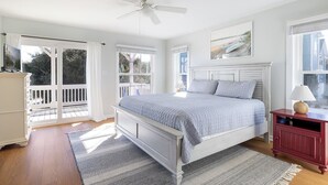 A bedroom with a bed, a nightstand, a ceiling fan, and a window. - Flip Flop Inn, Almost Oceanfront Duplex in Emerald Isle, NC! (Emerald Isle)