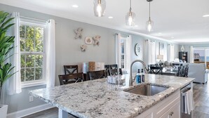 A spacious kitchen with a large island, pendant lights, and a view to the living area. - Footprints East, Oceanfront Duplex in Emerald Isle, NC! (Emerald Isle)