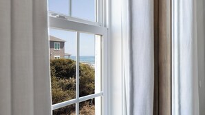 A window with a view of a house and ocean. - Footprints East, Oceanfront Duplex in Emerald Isle, NC! (Emerald Isle)