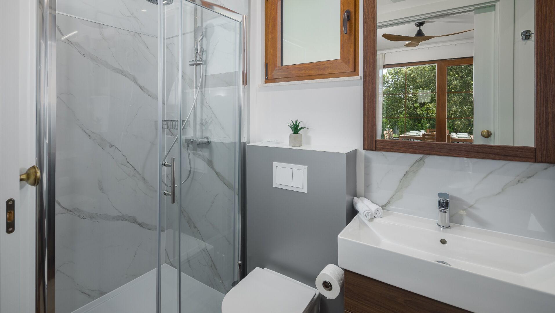 A bathroom with a glass shower enclosure, a white sink, and a mirror above the sink.