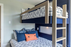 Un lit superposé avec une couvre-lit à motifs, des oreillers et une étagère recouverte d’un tissu à motifs.
