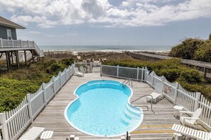 A swimming pool with a wooden deck, white chairs, and a view of the beach. - Susie's Ocean Retreat West, Oceanfront Duplex in Emerald Isle, NC! (Emerald Isle)