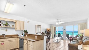 Een ruime woonkamer met een keuken, eettafel en een balkon met uitzicht op de oceaan.