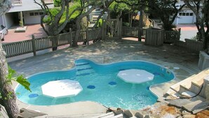 Piscina com deck de madeira e cerca de madeira ao redor.