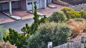 Um edifício residencial com vários andares, varandas, entrada pavimentada e vegetação ao redor.